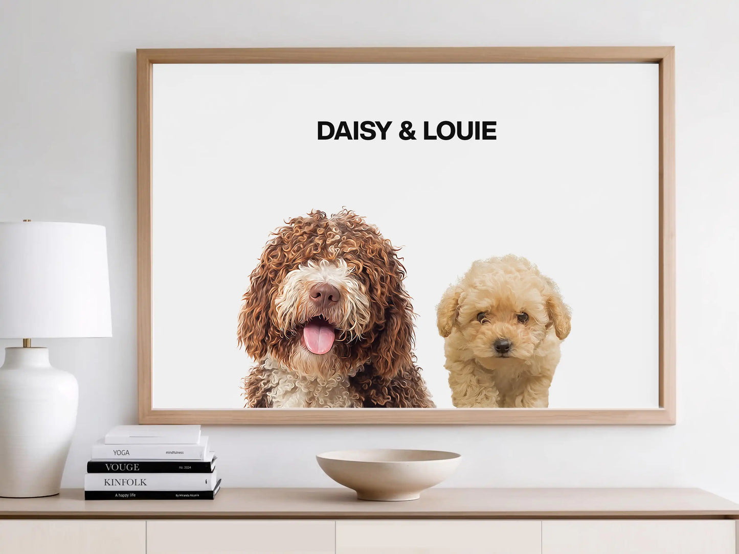 Framed digital portrait of two dogs, Daisy and Louie, displayed on a white wall above a console table. The artwork features hyper-realistic illustrations of a curly brown dog and a cream-colored poodle on a white background. Custom pet wall print by JupiterStarCo.