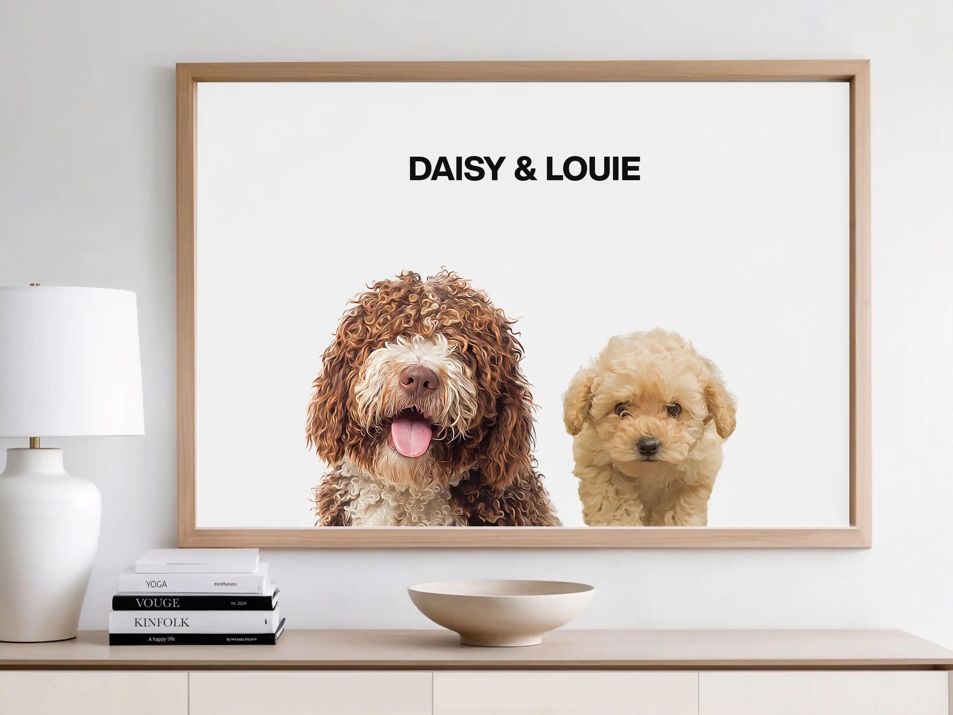 Framed digital portrait of two dogs, Daisy and Louie, displayed on a white wall above a console table. The artwork features hyper-realistic illustrations of a curly brown dog and a cream-colored poodle on a white background. Custom pet wall print by JupiterStarCo.